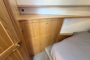 Wooden interior of 2024 Piper 12c, featuring built-in storage and cozy bed area.