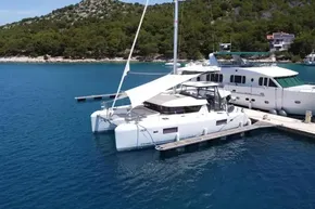 2024 Lagoon 42 catamaran docked in serene marina with lush green backdrop.