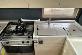 Modern kitchen in 2023 Beneteau Oceanis 51.1 yacht with stove, sink, and kettle.