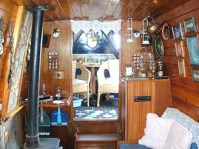 Living space with multi fuel stove, settee and storage, leading to front deck with a cratch and covers.