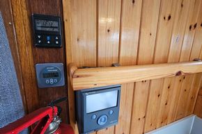 Wood-paneled interior of a 1921 Classic Dutch Barge with modern control panels and fire extinguisher.