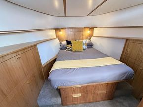 Cozy bedroom in 2024 Piper 12c boat with modern wood furnishings and ambient lighting.