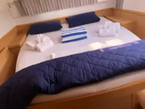 Cozy bedroom in a 2020 Lagoon 42 catamaran with neatly arranged towels and bedding.