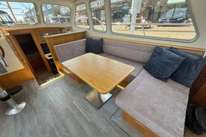 Modern interior of 2024 Piper 12c boat with cozy seating and wooden table.