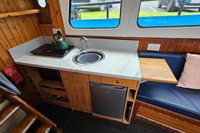 Cozy 1921 Classic Dutch Barge kitchen with wooden interior, sink, and seating area.
