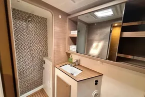Modern bathroom in 2024 Lagoon 42 yacht with shower, sink, and wood accents.