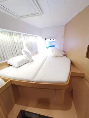 Interior cabin of 2020 Lagoon 42 catamaran with cozy bedding and natural light.