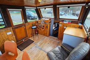 Interior of a 1921 Classic Dutch Barge with wooden paneling and steering wheel.