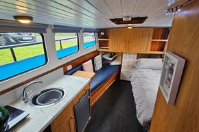 Interior of a 1921 Classic Dutch Barge with cozy living space and kitchenette.