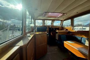 Interior of a 1994 Linssen 360 AC yacht with wooden furnishings and large windows.