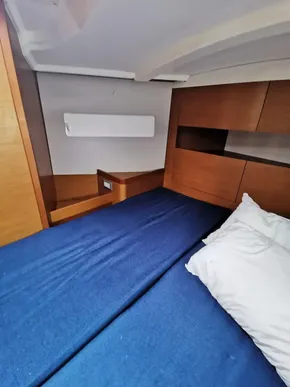 Interior cabin of 2020 Jeanneau Sun Odyssey 410 with blue bedding and wooden accents.