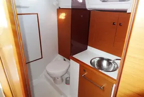 2017 Jeanneau Sun Odyssey 389 bathroom with sink, toilet, and wooden cabinetry.