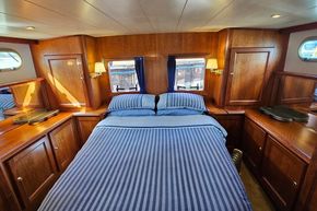 Luxurious cabin interior of 2005 Stevens 1200 Vlet yacht with wood finish and striped bedding.