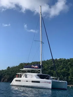 2020 Leopard 40 catamaran sailing on calm waters near a lush green coastline.