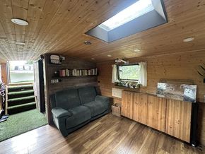 Bright, open-plan saloon with reclining sofa and overhead skylight.