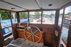 1926 Dutch Barge Luxemotor interior with wooden steering wheel and river view.