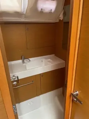 2017 Jeanneau Sun Odyssey 519 bathroom with wooden cabinetry and white sink.