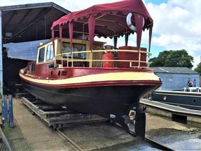 Classic 1927 Dutch barge with red canopy in dry dock.
