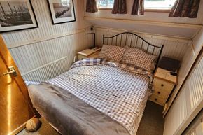 Cozy bedroom with checkered bedding in a 1926 Dutch Barge Luxemotor.