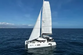 2024 Lagoon 42 catamaran sailing on open sea under clear blue sky.