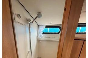 Shower area in 2025 Linssen 45 SL Sedan yacht with wooden accents and window.