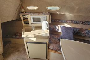 1999 Wellcraft 2400 Martinique cabin interior with kitchenette, sink, and seating area.