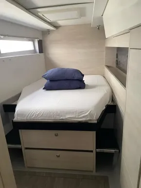 Compact bedroom in a 2020 Leopard 50 yacht, featuring a neatly made bed with blue pillows.