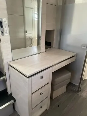 Modern vanity area in Leopard 50 yacht, featuring drawers, mirror, and cushioned stool.
