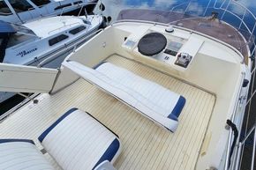 1989 Princess 35 Flybridge yacht deck with seating and controls, docked beside another boat.