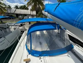 2019 Jeanneau Sun Odyssey 440 sailboat with blue canopy, docked near palm trees.