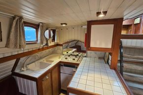 Cozy 1926 Dutch Barge Luxemotor kitchen with tiled countertops and wooden cabinetry.