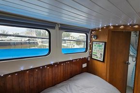 Cozy interior of a 1921 Classic Dutch Barge with wooden paneling and marina view.