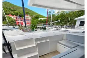 Leopard 45 catamaran deck with seating, docked near colorful buildings and lush greenery.