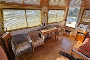 Interior of a 1927 Classic Dutch Barge with wicker chairs and wooden decor.