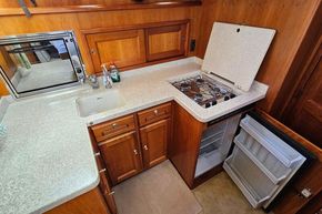 Compact kitchen in a 2005 Stevens 1200 Vlet boat with stove, sink, and fridge.