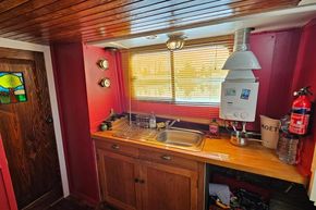 1927 Classic Dutch Barge kitchen with wooden cabinets, sink, and nautical decor.