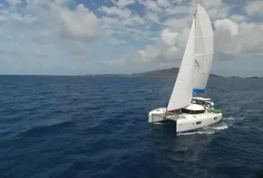Lagoon 42 catamaran sailing in open sea, 2020 model, under a partly cloudy sky.