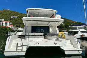 2022 Leopard 53 Powercat yacht docked in a marina, surrounded by lush green hills.