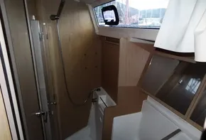 Beneteau Oceanis 41 2017 bathroom with shower, wooden cabinetry, and porthole window.