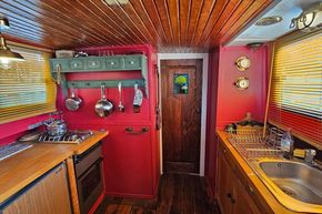 1927 Classic Dutch Barge kitchen with wooden decor, red walls, and vintage accents.