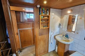 Luxemotor Dutch Barge 1926 bathroom with wooden cabinetry and tiled walls.